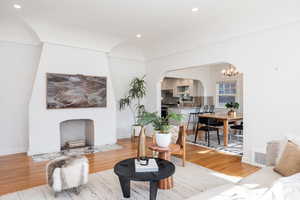 Living room featuring hanging lights, light wood-style floors, arched walkways, and a high end fireplace
