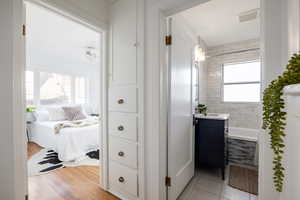 Ensuite bathroom with tiled shower / bath combo, vanity, and light tile patterned floors