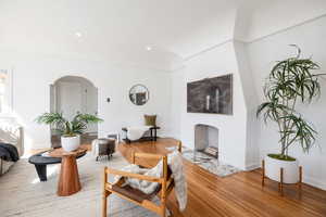 Living area with arched walkways, wood finished floors, and recessed lighting
