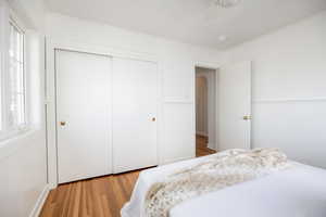Bedroom with light wood-type flooring, a closet, ceiling fan, a wainscoted wall, and crown molding