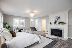 Bedroom with carpet flooring, ceiling fan, and a fireplace with flush hearth