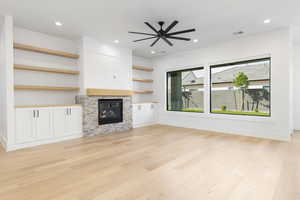 Unfurnished living room with a glass covered fireplace, a ceiling fan, light wood-type flooring, and recessed lighting