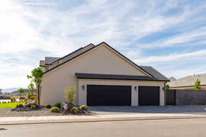 View of home's exterior with a garage, decorative driveway, stucco siding, and a tiled roof