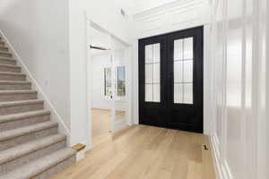 Foyer entrance featuring light wood finished floors and french doors