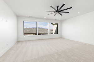Spare room with a mountain view, ceiling fan, light carpet, and recessed lighting