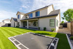 Rear view of house with a fenced backyard, a patio area, a trampoline, and stucco siding