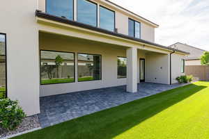 Rear view of property featuring stucco siding, a patio area, and a lawn