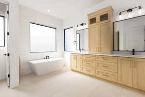Full bathroom with double vanity, tile walls, a soaking tub, light tile patterned flooring, and recessed lighting