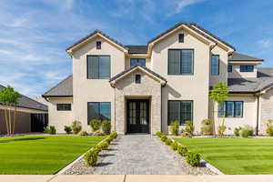 View of front facade featuring a front lawn, stucco siding, and a tiled roof