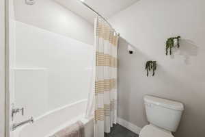 Bathroom featuring shower / tub combo with curtain and dark tile patterned floors