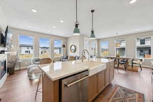 Kitchen with open floor plan, stainless steel dishwasher, pendant lighting, and light wood-style flooring