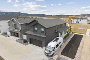 View of front of property featuring an attached garage, a mountain view, driveway, and a shingled roof