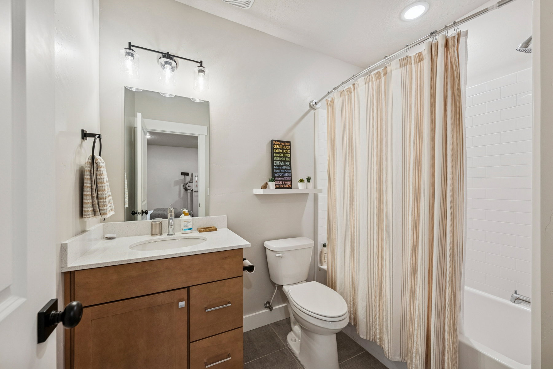 Bathroom with vanity, shower / tub combo, and dark tile patterned flooring