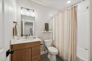 Bathroom with vanity, shower / tub combo, and dark tile patterned flooring