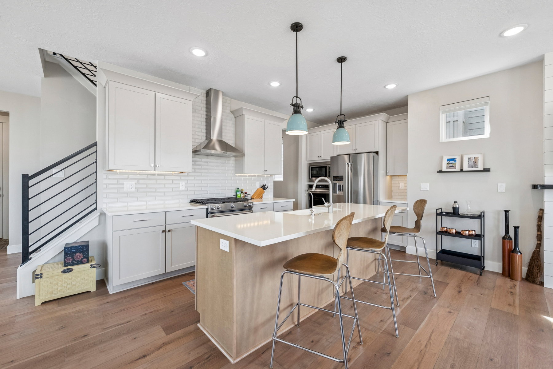 Dual tone kitchen with an island with sink, a breakfast bar area, high end appliances, two tone cabinets, and dark wood finished floors