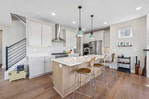 Dual tone kitchen with an island with sink, a breakfast bar area, high end appliances, two tone cabinets, and dark wood finished floors