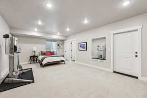 Bedroom with light carpet, a textured ceiling, and recessed lighting