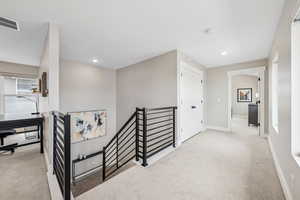 Hall featuring an upstairs landing, light colored carpet, and recessed lighting