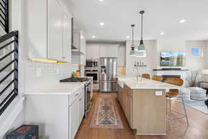 Kitchen with two tone color scheme, a breakfast bar, stainless steel appliances, open floor plan, and a center island with sink