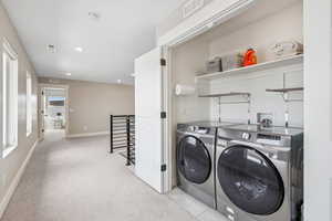 Laundry area with washing machine and clothes dryer, light colored carpet, and recessed lighting