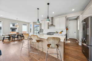 Kitchen with high quality appliances, a center island with sink, dark wood-style flooring, and hanging light fixtures