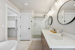 Bathroom with double vanity, a soaking tub, a shower stall, light tile patterned flooring, and a walk in closet