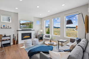 Living room with wood-type flooring, a glass covered fireplace, plenty of natural light, and recessed lighting