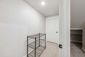 Hall with a textured ceiling and light colored carpet