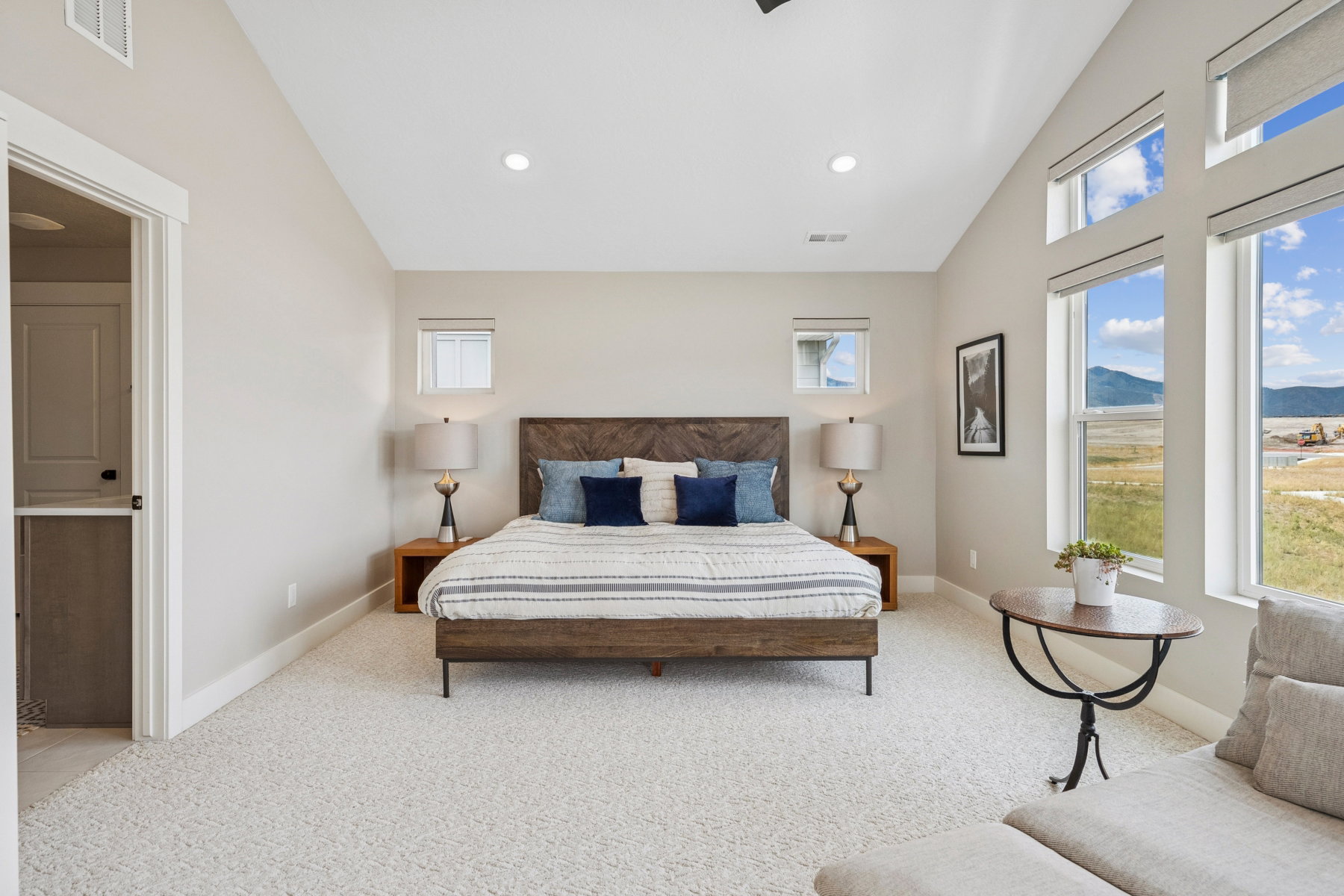 Bedroom with vaulted ceiling, light carpet, a mountain view, and recessed lighting