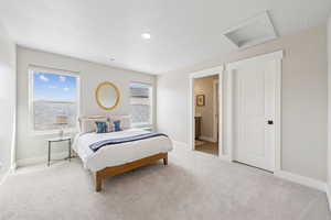 Bedroom with light carpet, connected bathroom, and a textured ceiling