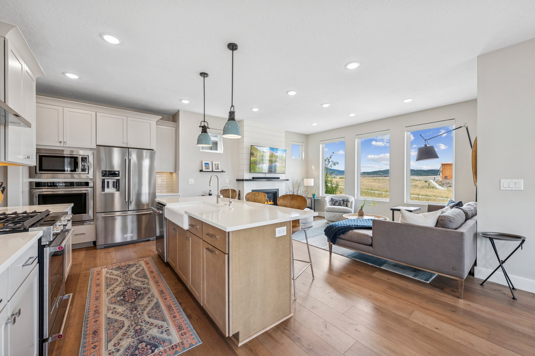 Dual tone kitchen with high quality appliances, open floor plan, two tone color scheme, dark wood-style floors, and a center island with sink