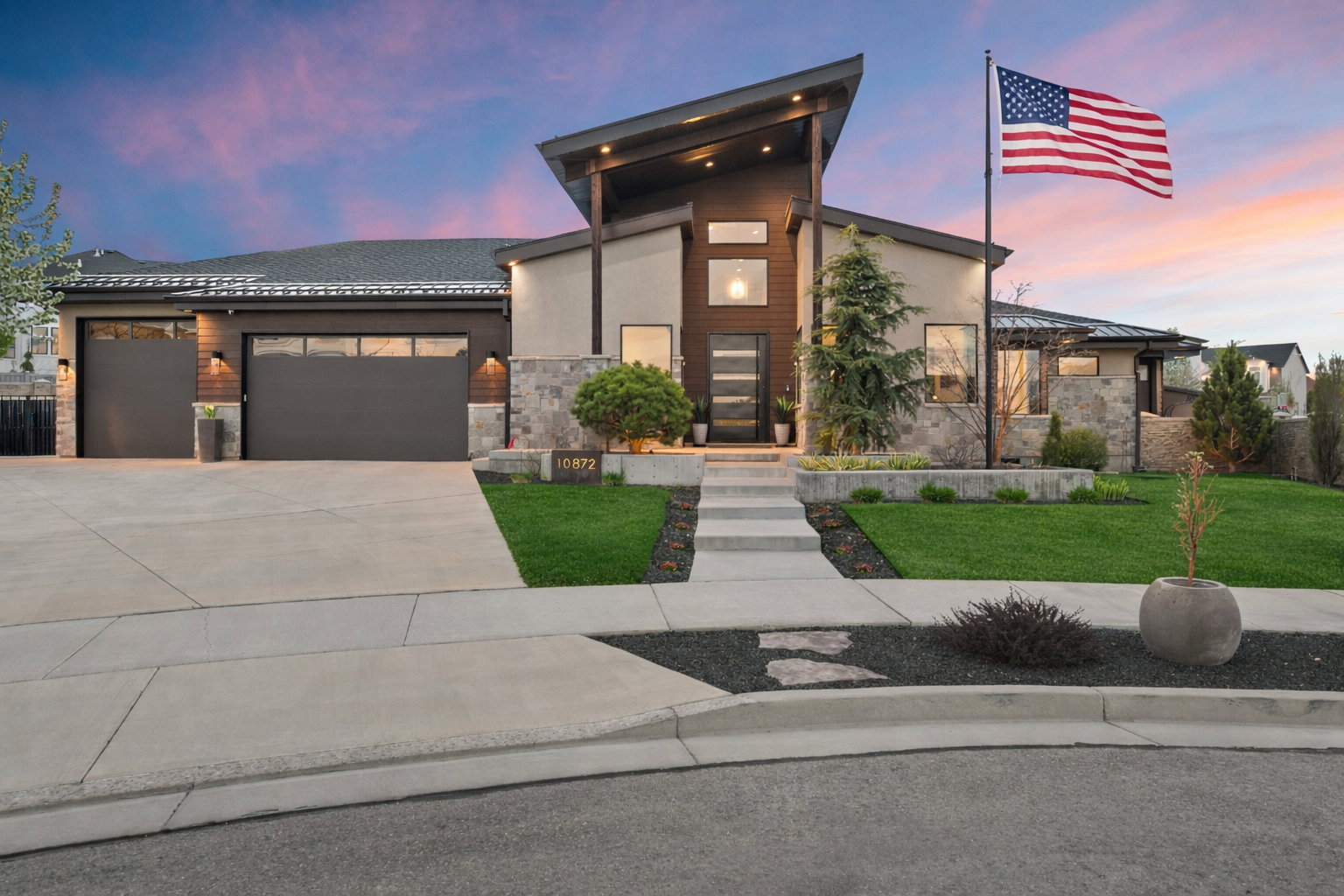 Contemporary home with stone siding, a garage, concrete driveway, and stucco siding