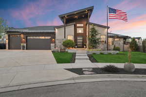 Contemporary home with stone siding, a garage, concrete driveway, and stucco siding