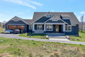 Craftsman-style house featuring asphalt driveway, a front yard, covered porch, an attached garage, and a shingled roof