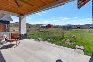 View of back patio featuring a trampoline, a mountain view, an outdoor structure, and a view of rural / pastoral area