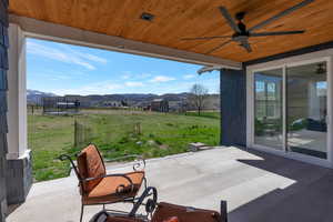 View of back patio / terrace featuring ceiling fan, a trampoline, and a mountain view