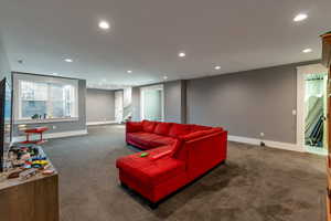 Living area featuring dark colored carpet and recessed lighting