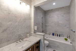 Full bathroom with tile walls, vanity, recessed lighting, and a combined bath / shower with marble appearance