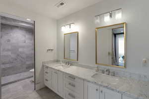 Full bathroom with double vanity and a tile shower