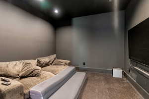 Home theater with dark colored carpet and baseboards