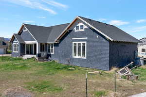 View of front of property with a porch, a shingled roof, and a front yard