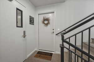 Entryway featuring stairs and light colored carpet