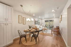 Dining room with light wood-style flooring and suspended lighting