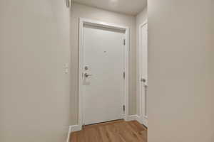 Doorway to outside with wood finished floors and baseboards