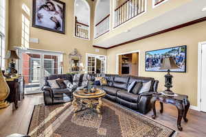Living area featuring hardwood / wood-style flooring, a high ceiling, and ornamental molding