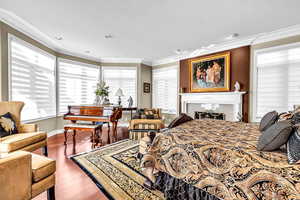 Bedroom featuring dark wood-style floors, ornamental molding, recessed lighting, and a tile fireplace