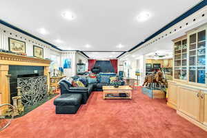 Carpeted living room with a fireplace with flush hearth and crown molding