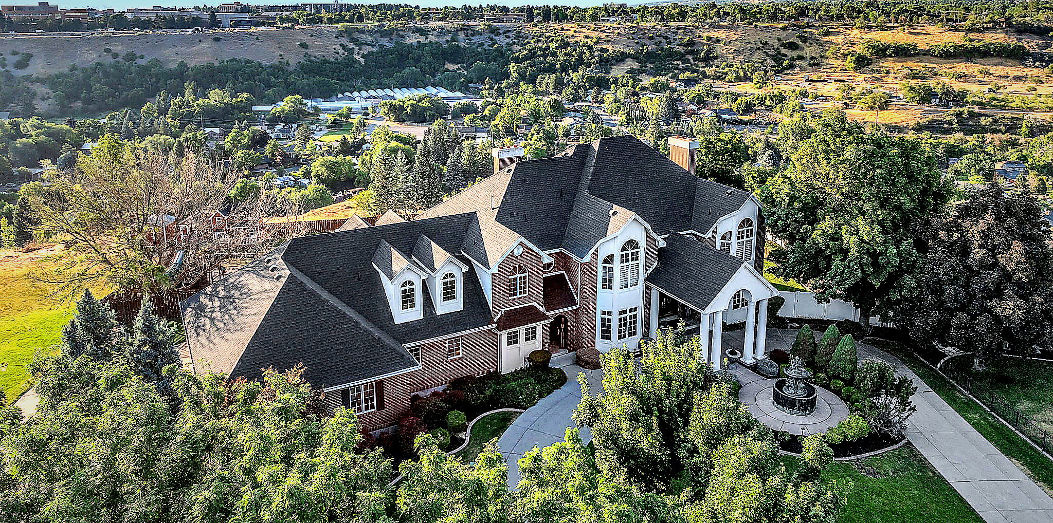 Aerial view of property and surrounding area featuring a tree filled landscape