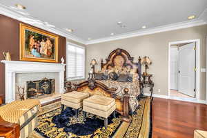Bedroom featuring ornamental molding, wood finished floors, a tiled fireplace, and recessed lighting