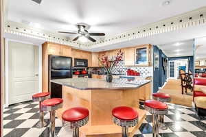 Kitchen featuring light flooring, crown molding, glass insert cabinets, a kitchen island, and tasteful backsplash